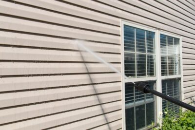 Pressure washing service in Nocatee, Florida, cleaning siding with water spray near residential windows.