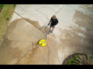 Pressure washing technician using a surface cleaner on a concrete patio, showcasing professional cleaning services offered by Spray Down Exterior Cleaning in St. Augustine, Florida.